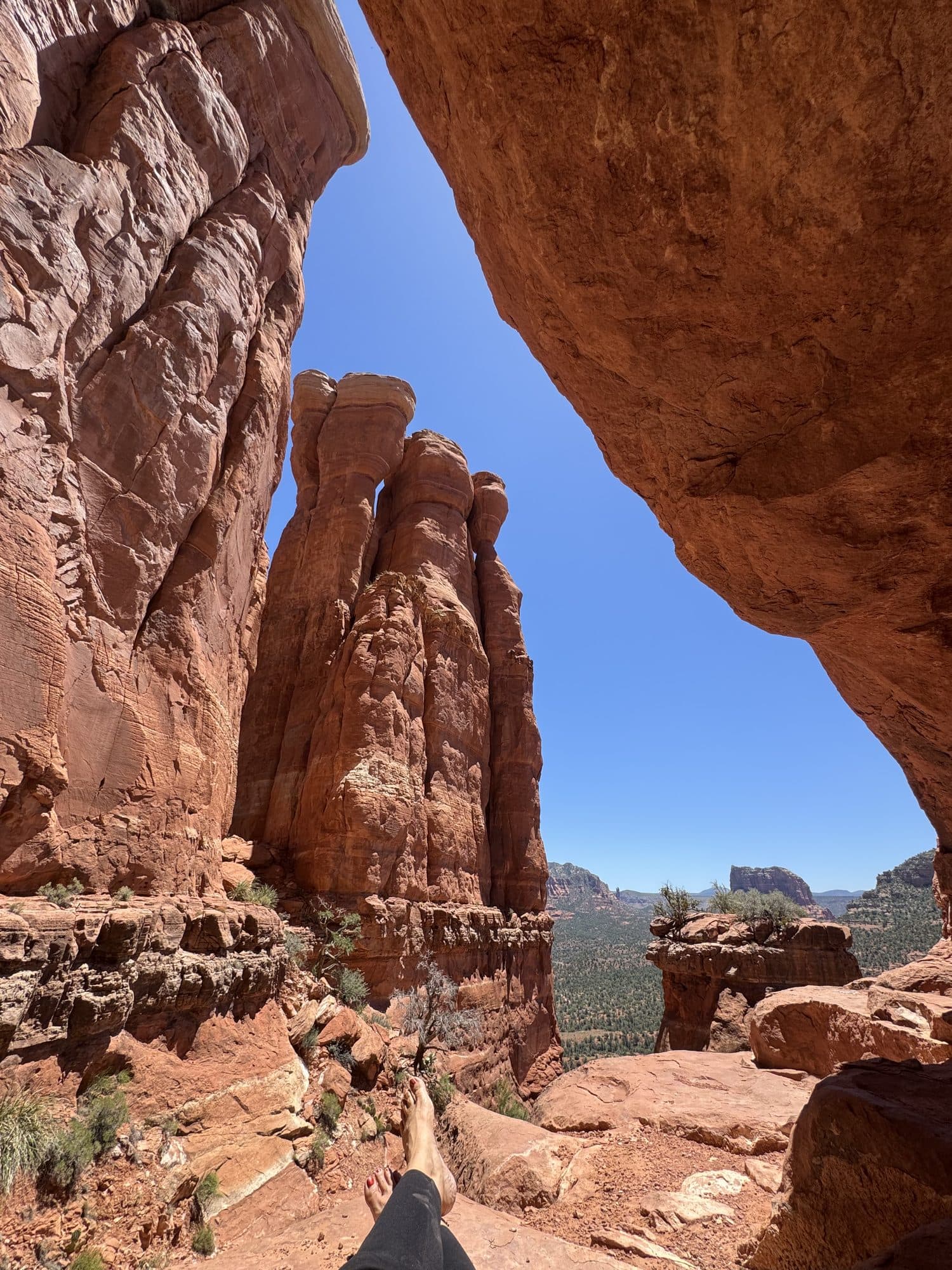Looking out from the shade of a red rock overhang to the cliffs and sky beyond