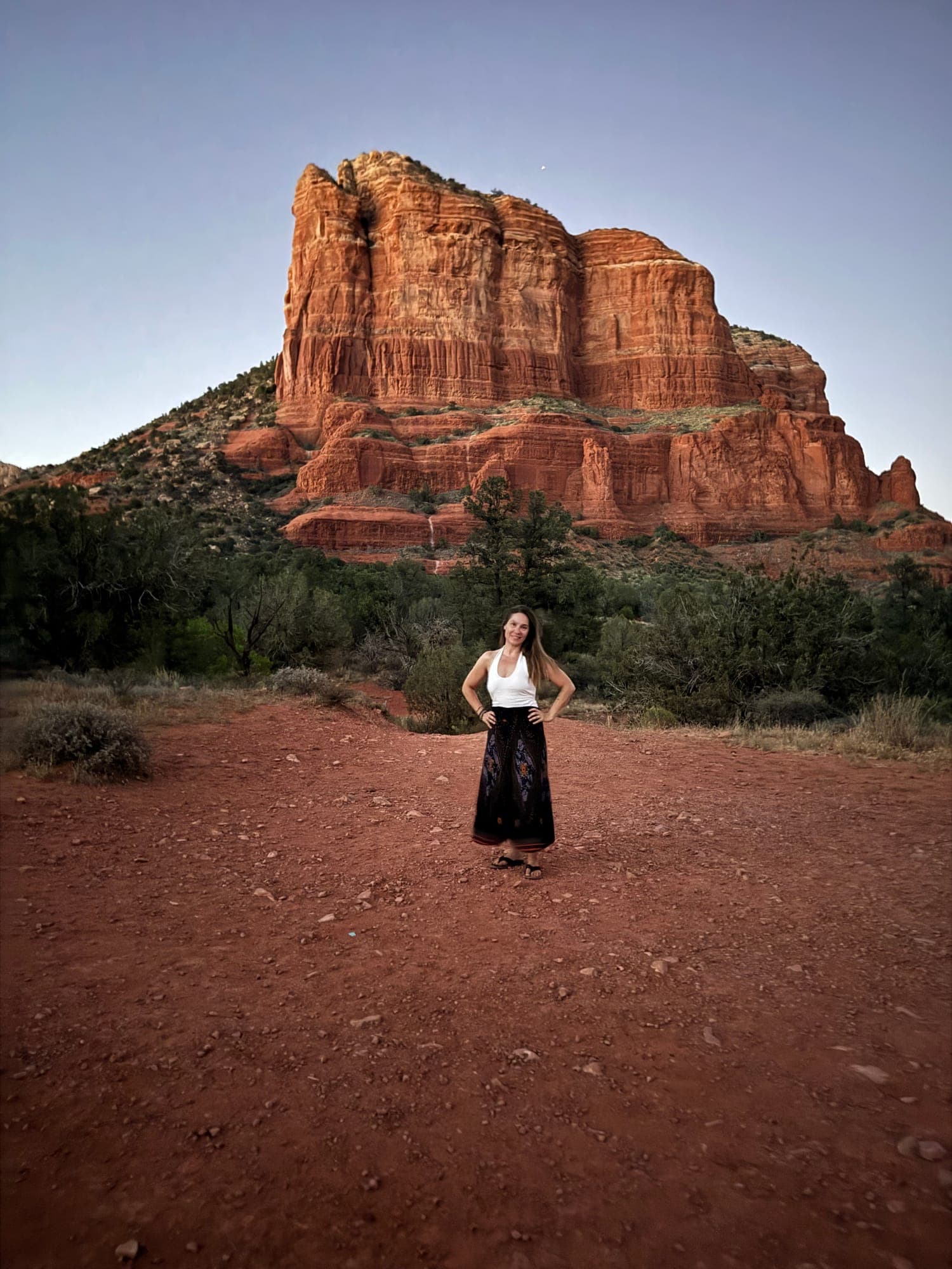 Rachel standing small below a red rock butte in Sedona