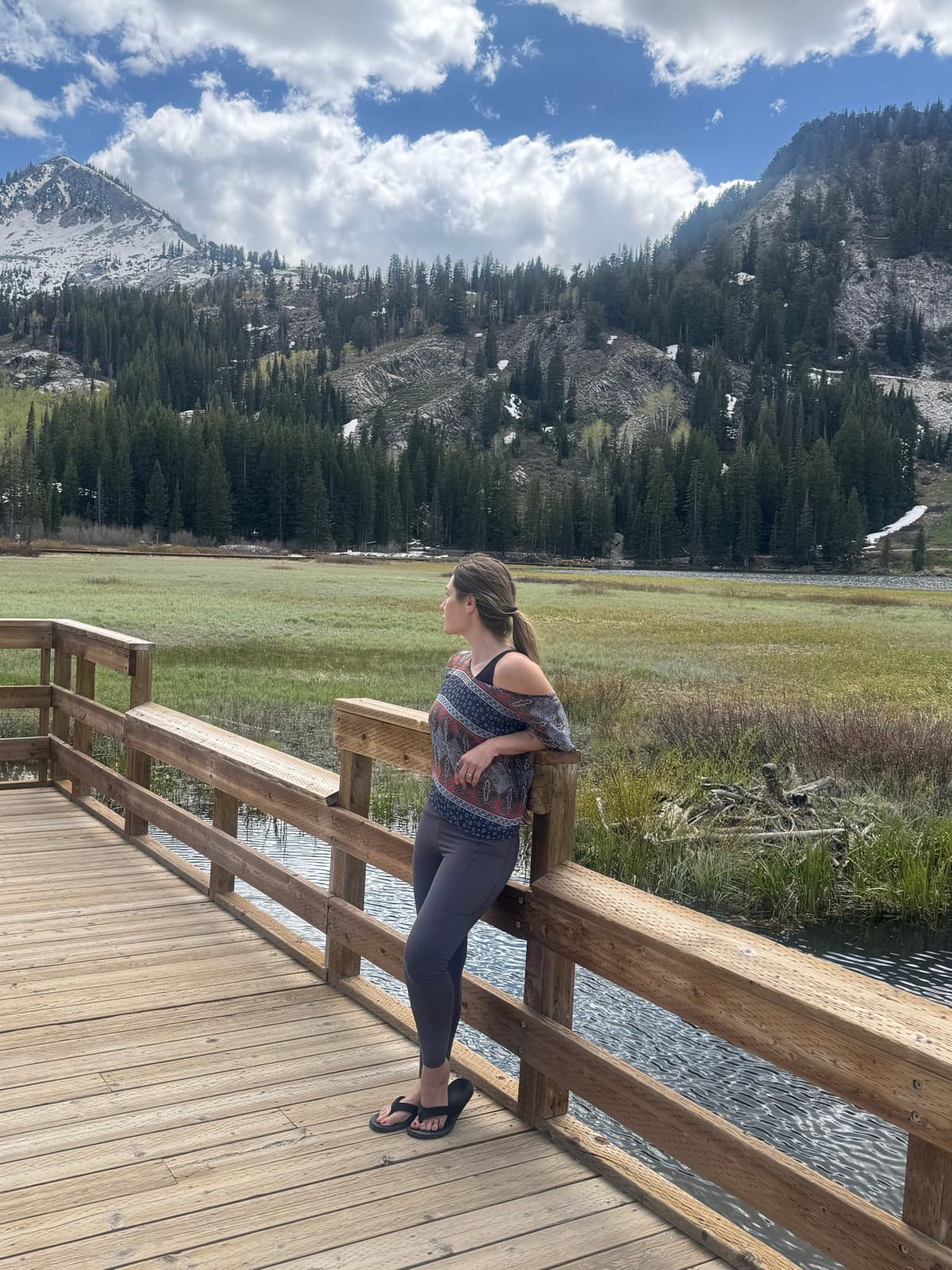 Rachel Patten on a mountain boardwalk looking out at alpine peaks, a quiet moment of reflection