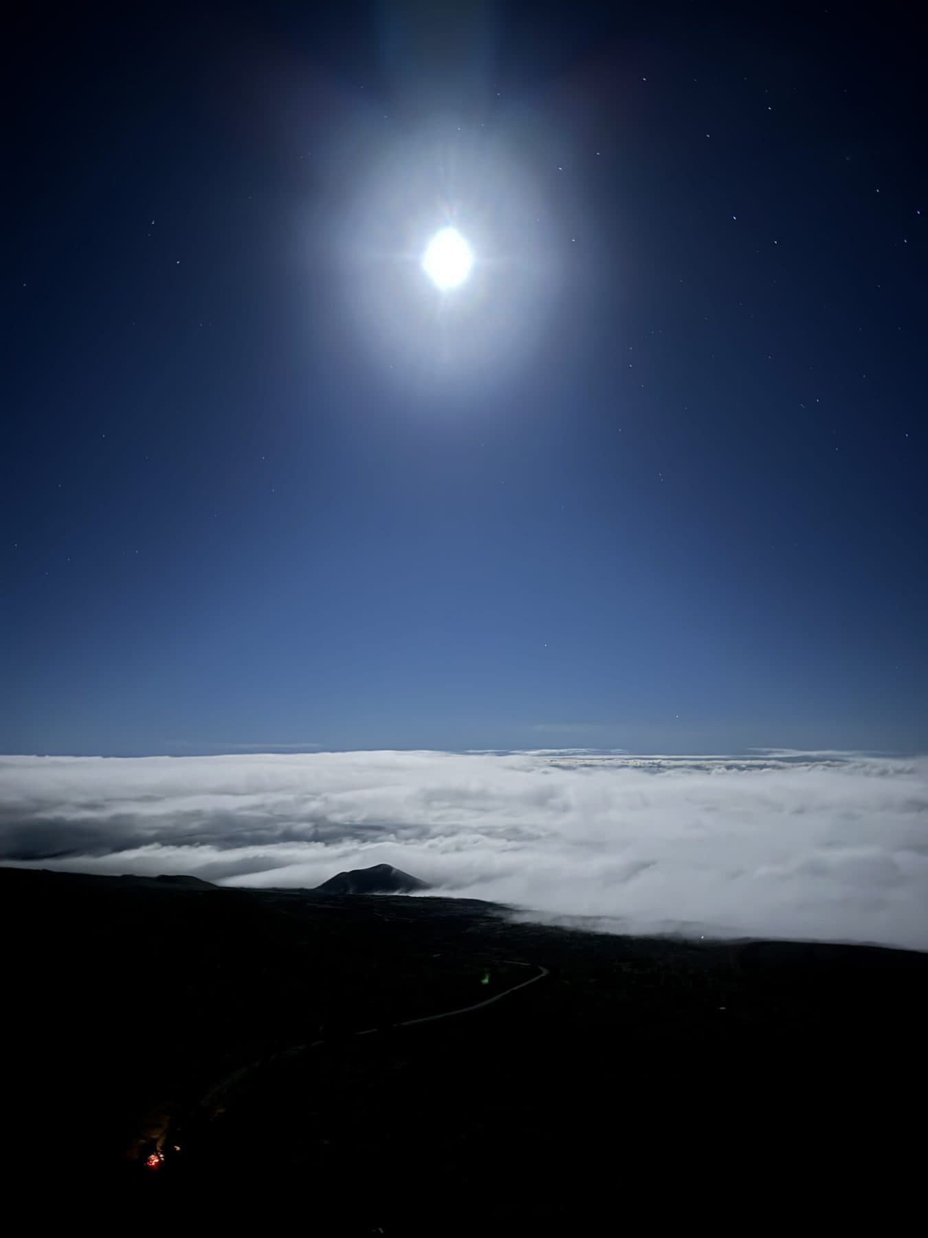 The moon shining above a sea of clouds from the mountain at night