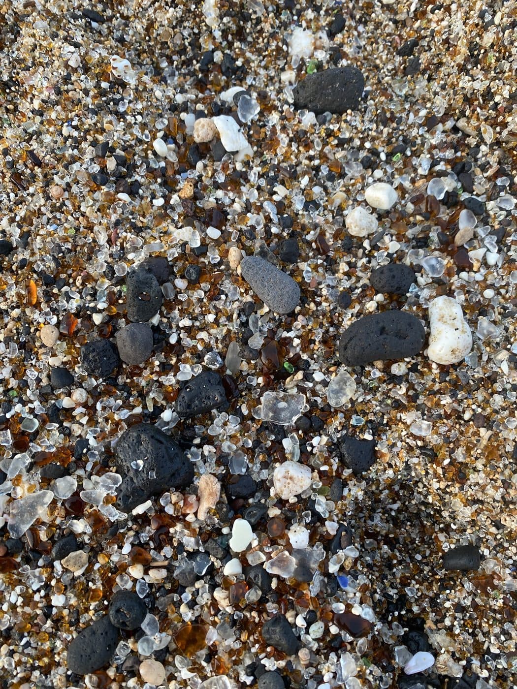 Sea glass and black pebbles worn smooth on a Hawaiian shore