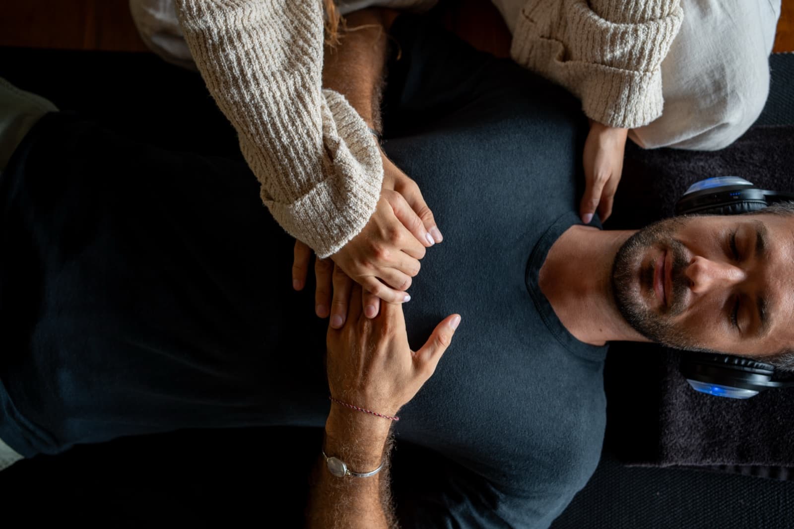 A practitioner's hands on a man's chest as he breathes in a headset