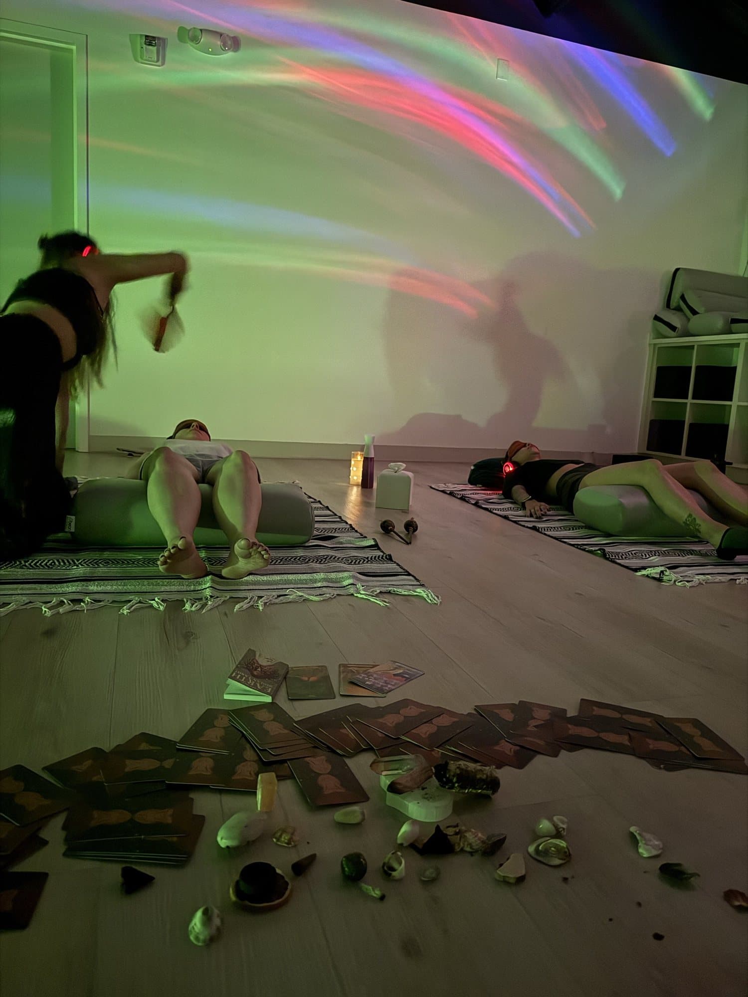 Rachel moving a fan above a group lying on mats, soft aurora light across the walls