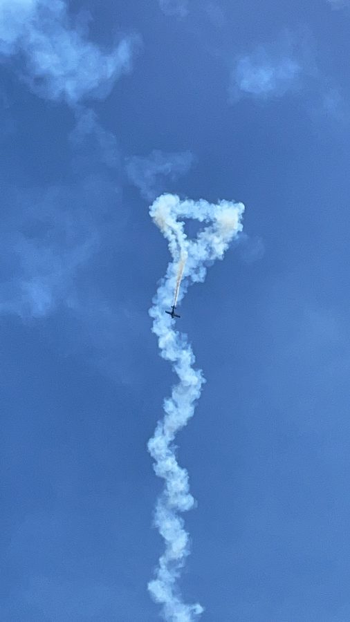 A plane's white smoke trail looping down a clear blue sky