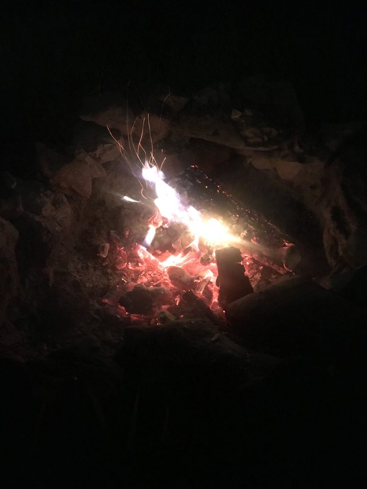 Embers glowing and a small flame in the dark
